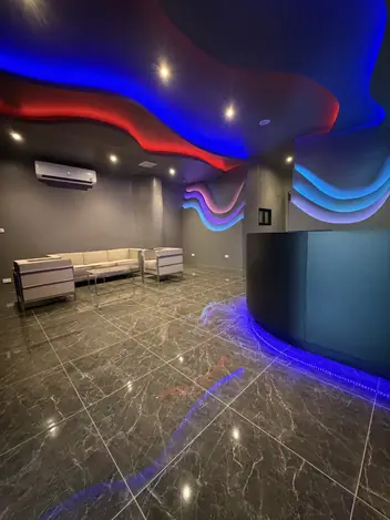 Aries Nuru Pattaya: lounge with a wavy neon ceiling and marble floor