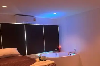 PlayTime Massage: room with a massage bed and corner jacuzzi under blue light